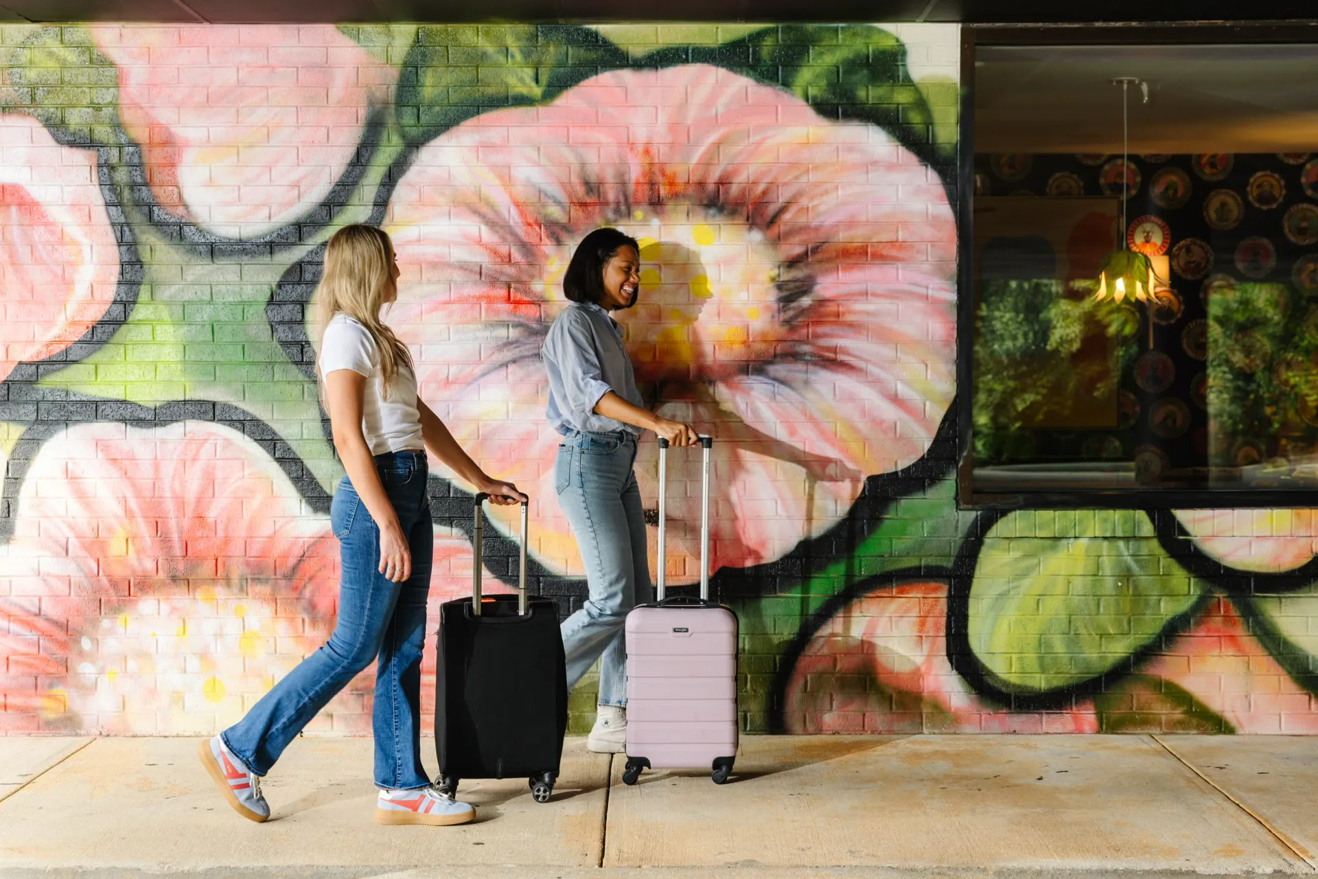 Guests arriving together beside the floral mural at Hive House